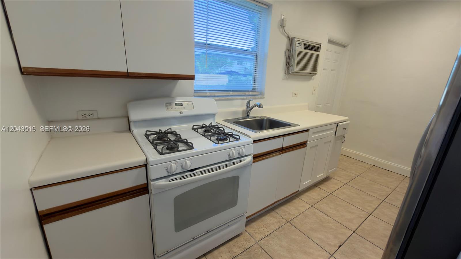 A kitchen features white cabinets, a gas stove, a sink, and a window air conditioner — 808 84th St # 810, Miami Beach FL 33141, MIAMI BEACH, FL