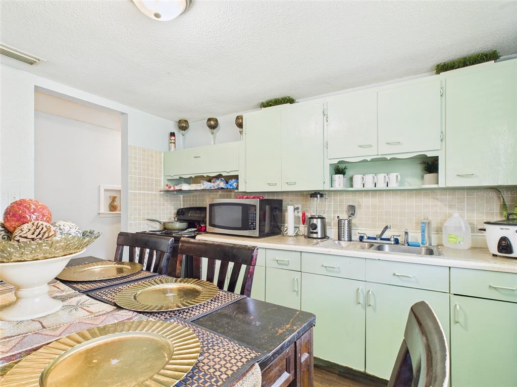 A kitchen features light green cabinets, a microwave, a sink, and a dining table — 2119 W PATTERSON STREET, LAKELAND, FL