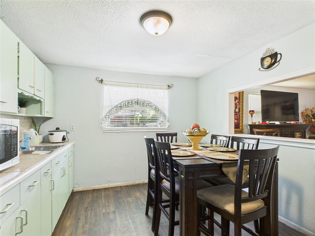 A dining area with light green cabinets, a dark wood table, and a pass-through window — 2119 W PATTERSON STREET, LAKELAND, FL