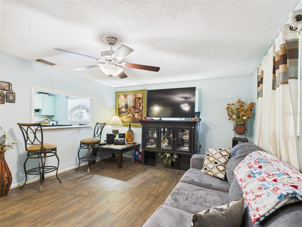 A living room features a grey sofa, a television on a cabinet, and two bar stools — 2119 W PATTERSON STREET, LAKELAND, FL