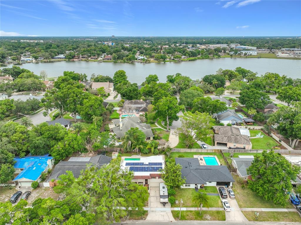 An aerial view shows suburban houses with pools and solar panels near a large lake — 1511 GLASTONBERRY ROAD, MAITLAND, FL