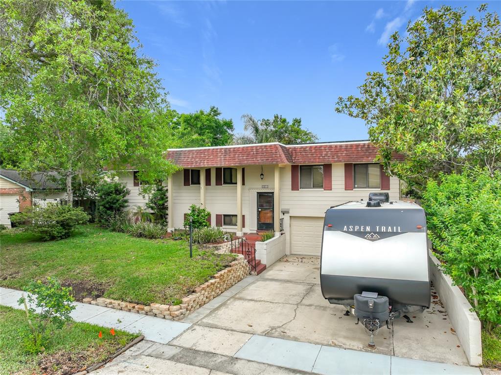 A split-level house with a red shingled roof and a travel trailer in the driveway — 1511 GLASTONBERRY ROAD, MAITLAND, FL