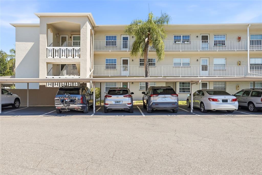 A screened-in balcony features two wicker chairs with tropical-print cushions and a small round table — 952 VIRGINIA STREET UNIT 202, DUNEDIN, FL