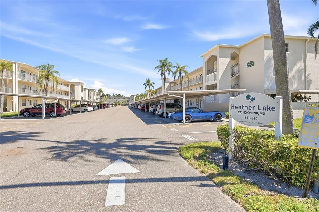A multi-story apartment building with a covered parking area and several parked cars — 952 VIRGINIA STREET UNIT 202, DUNEDIN, FL