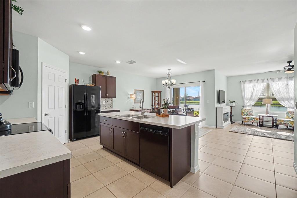 A kitchen with dark cabinets and an island opens into a living area with tile floors — 7048 WATERFORD PARKWAY, PUNTA GORDA, FL