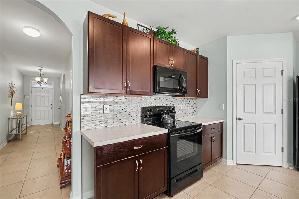 A kitchen features dark wood cabinets, a central island with two stools, and tile flooring — 7048 WATERFORD PARKWAY, PUNTA GORDA, FL