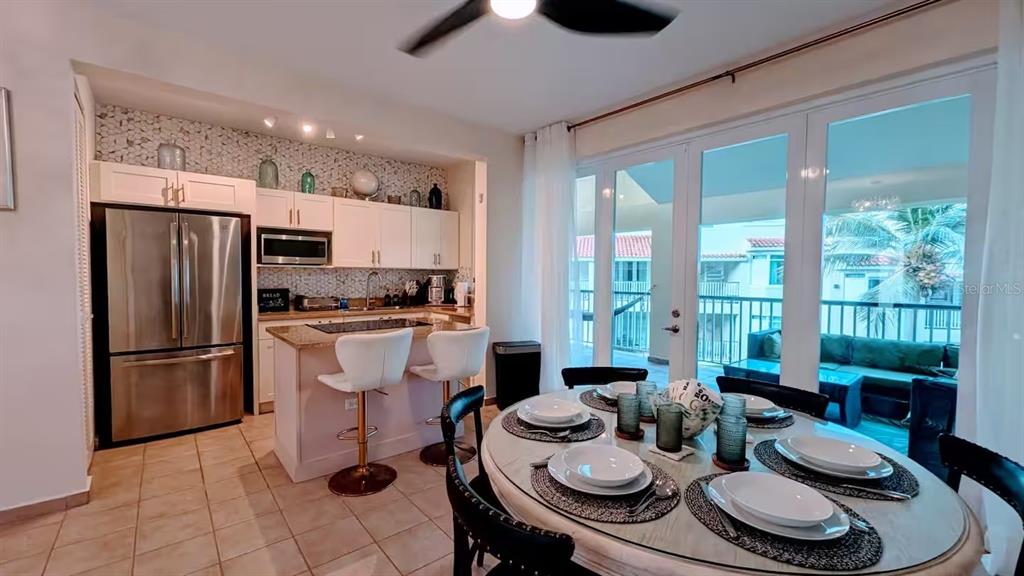A kitchen with white cabinets and a dining area featuring a round table and chairs — 180 PALMAS DRIVE UNIT 27C, HUMACAO, PR