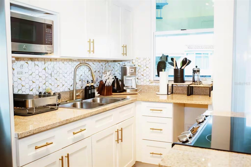 A kitchen features white cabinets, gold hardware, a tiled backsplash, and granite countertops — 180 PALMAS DRIVE UNIT 27C, HUMACAO, PR