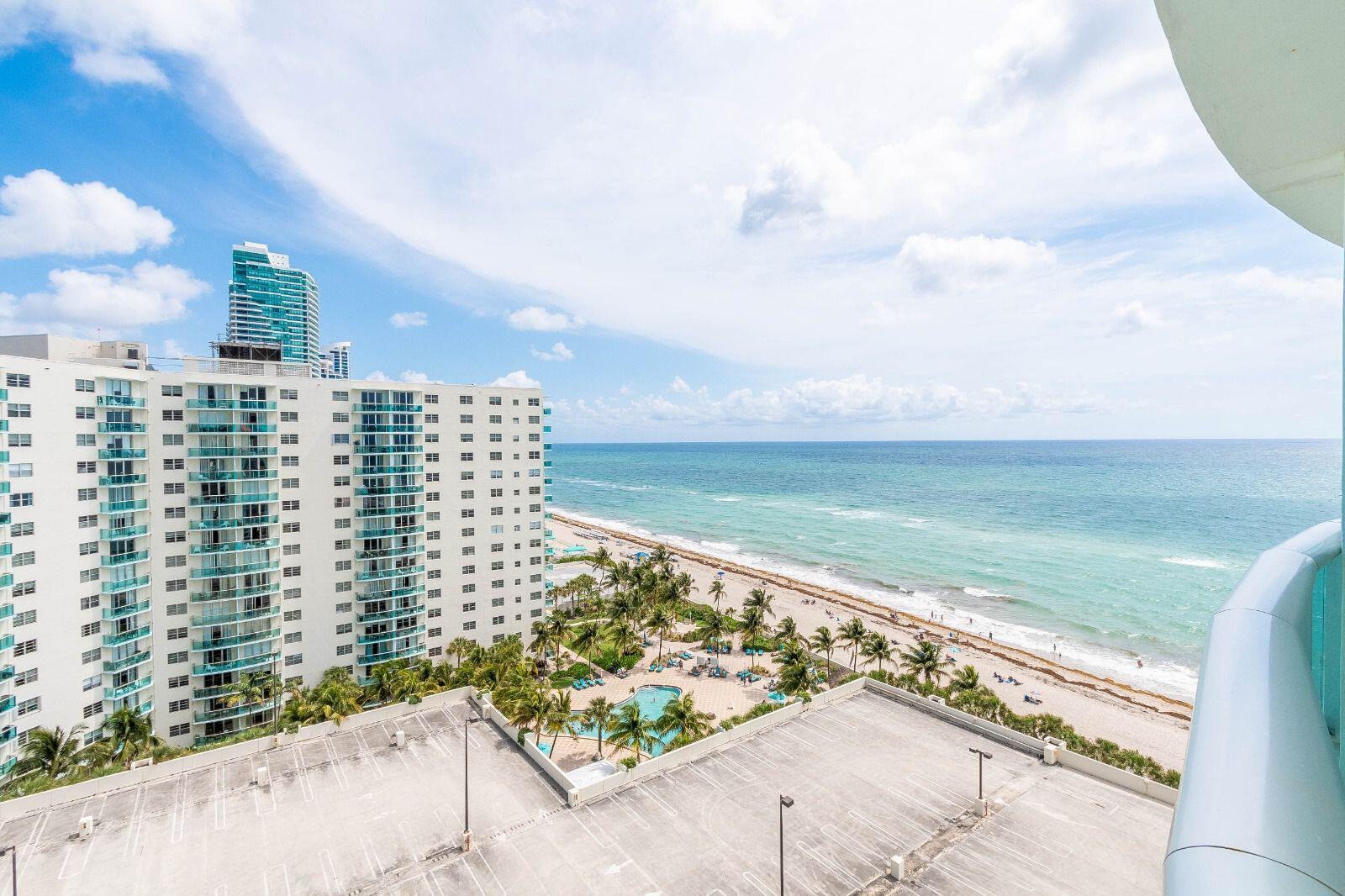 An elevated view of a beach, ocean, parking lot, and a tall residential building — 3901 S Ocean Drive # 14c, Hollywood FL 33019, HOLLYWOOD, FL