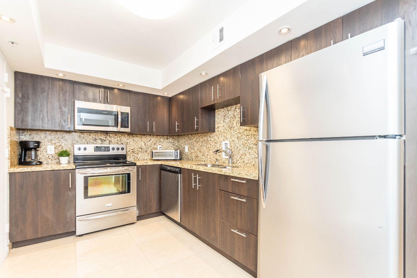 A kitchen with dark wood cabinets, granite countertops, and stainless steel appliances — 3901 S Ocean Drive # 14c, Hollywood FL 33019, HOLLYWOOD, FL