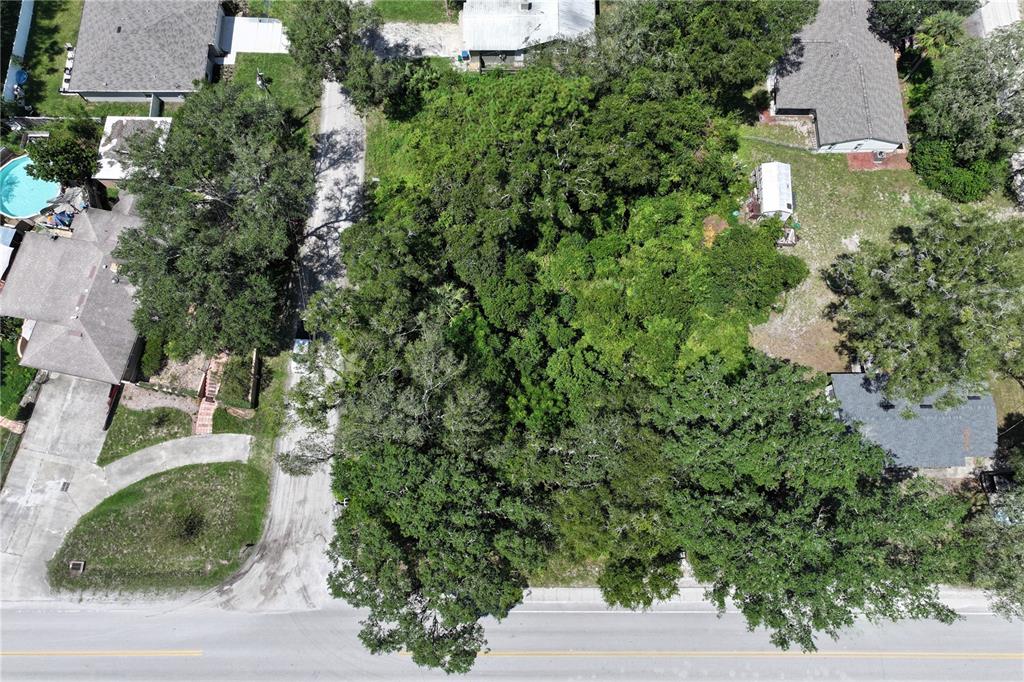 An aerial view shows a wooded, undeveloped rectangular lot situated between two residential properties — 14TH  ST, ORANGE CITY, FL