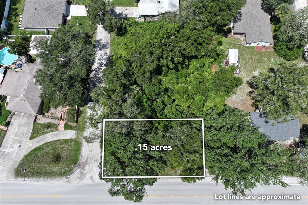 An aerial view shows a rectangular, tree-covered vacant lot outlined in white along a road — 14TH  ST, ORANGE CITY, FL