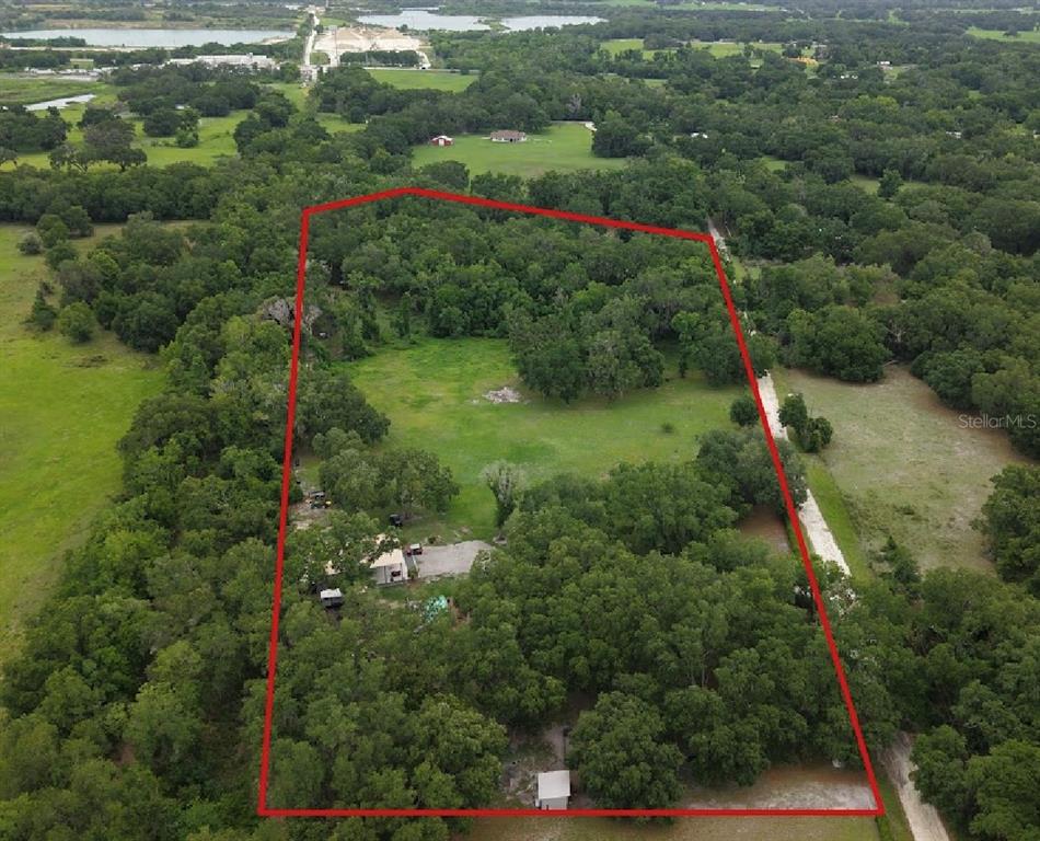 An aerial view shows a large, wooded plot of land outlined in red — 528 ASHLEY LANE, CENTER HILL, FL