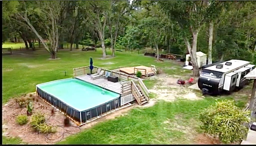An aerial view shows an above-ground swimming pool with a wooden deck and a camper — 528 ASHLEY LANE, CENTER HILL, FL
