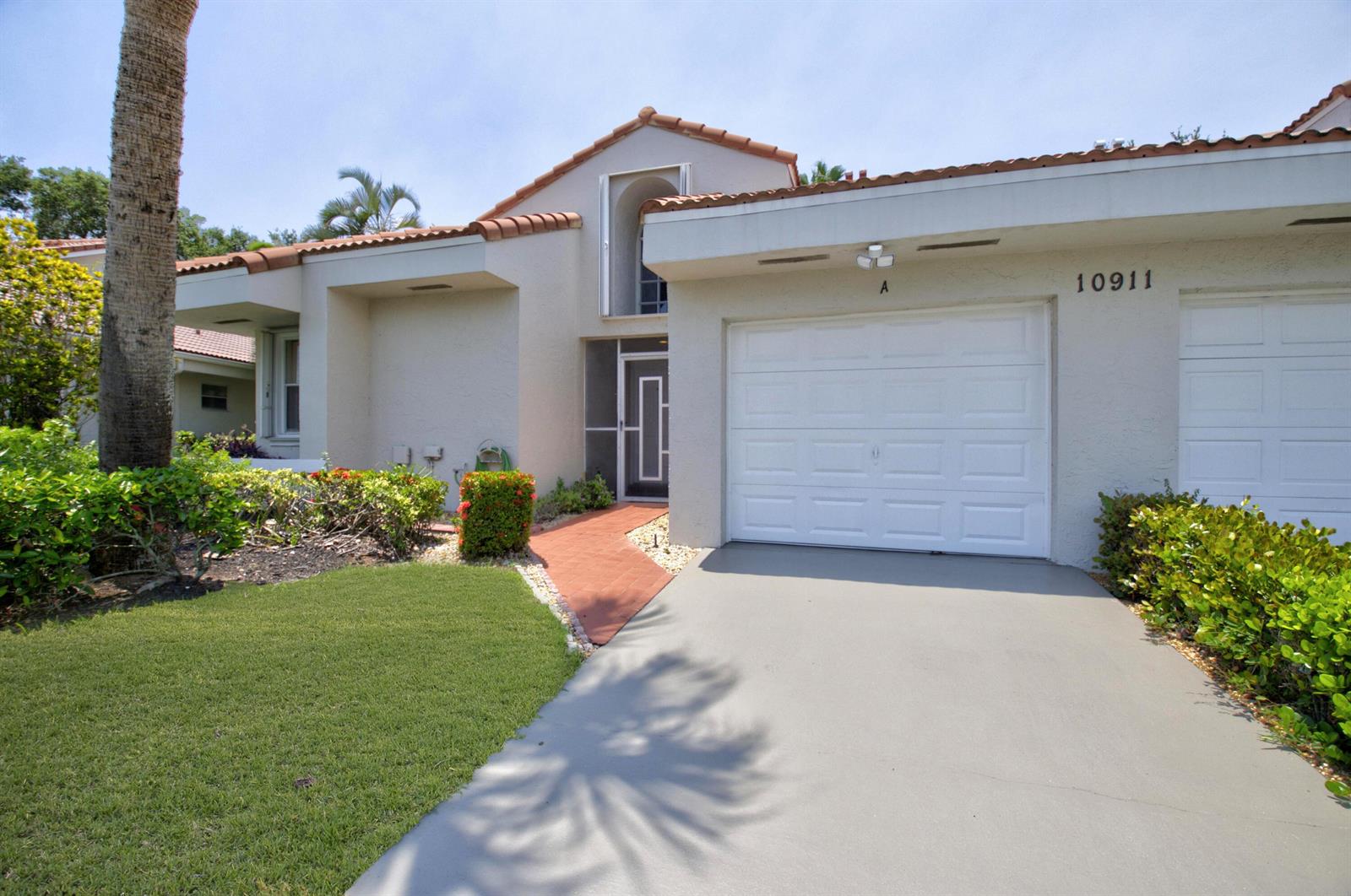 The exterior of a single-story home features a white garage, tiled roof, and walkway — 10911 Ladera Lane # A, Boca Raton FL 33498, BOCA RATON, FL