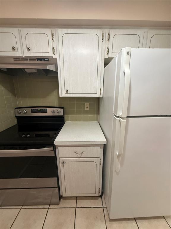 A kitchen features white cabinets, a black electric stove, and a white refrigerator — 4244 SHELDON PLACE UNIT 4244, NEW PORT RICHEY, FL