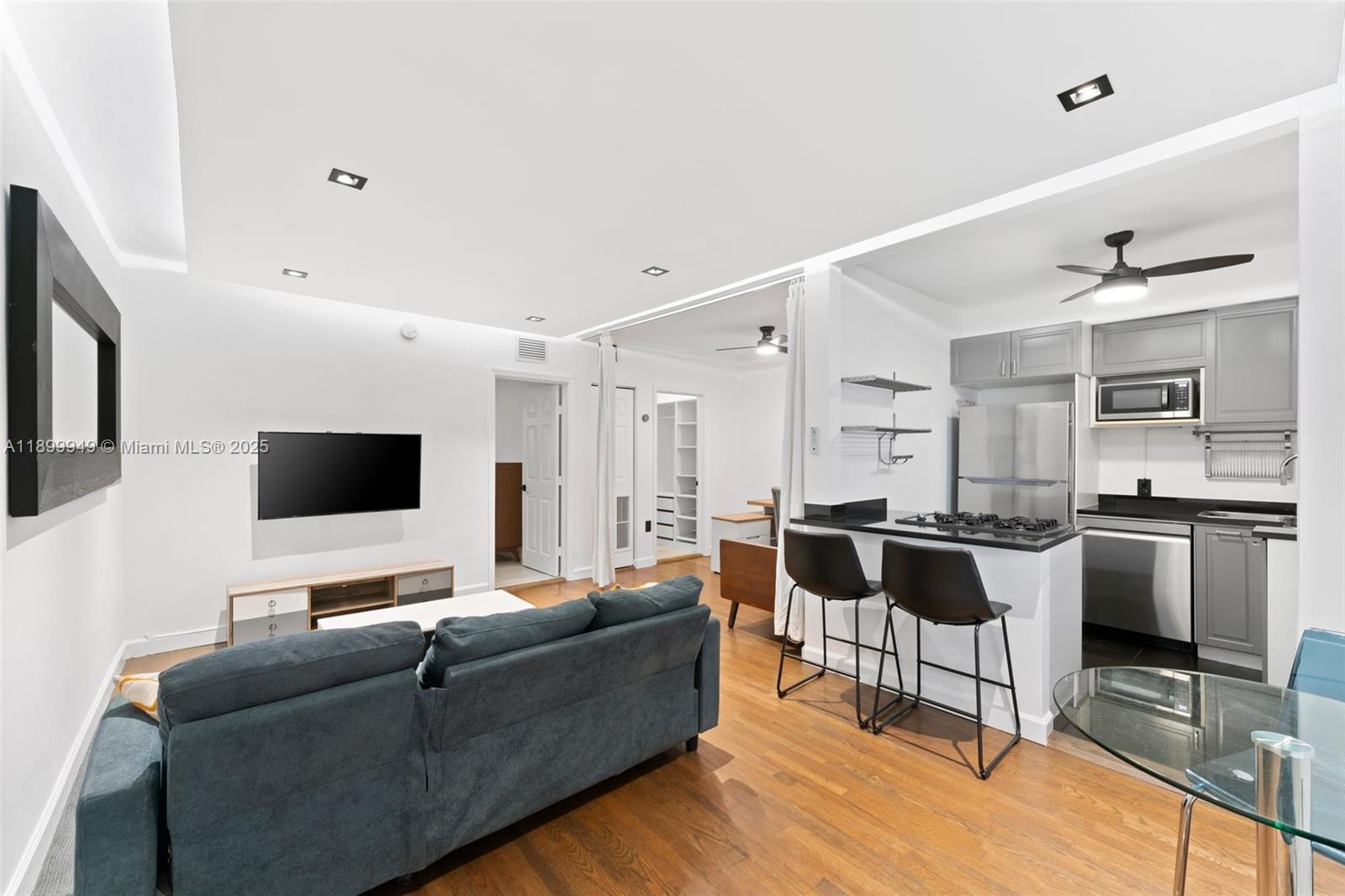 A living room with a sofa and TV connects to a kitchen with bar seating — 1515 WEST AVE # 9, Miami Beach FL 33139, MIAMI BEACH, FL