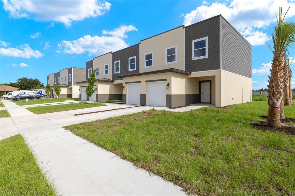 A row of modern two-story townhomes with garages and beige and dark gray siding — 14985 SUNSET EVE LOOP, FORT MYERS, FL