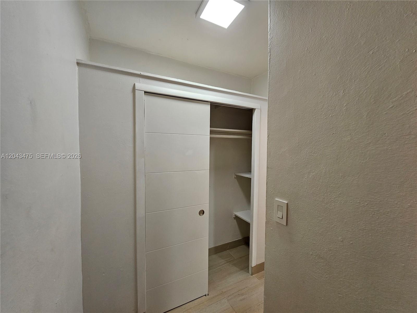 A closet with a sliding door and interior shelving is set within a neutral-toned room — 1723 Liberty St # 3, Hollywood FL 33020, HOLLYWOOD, FL