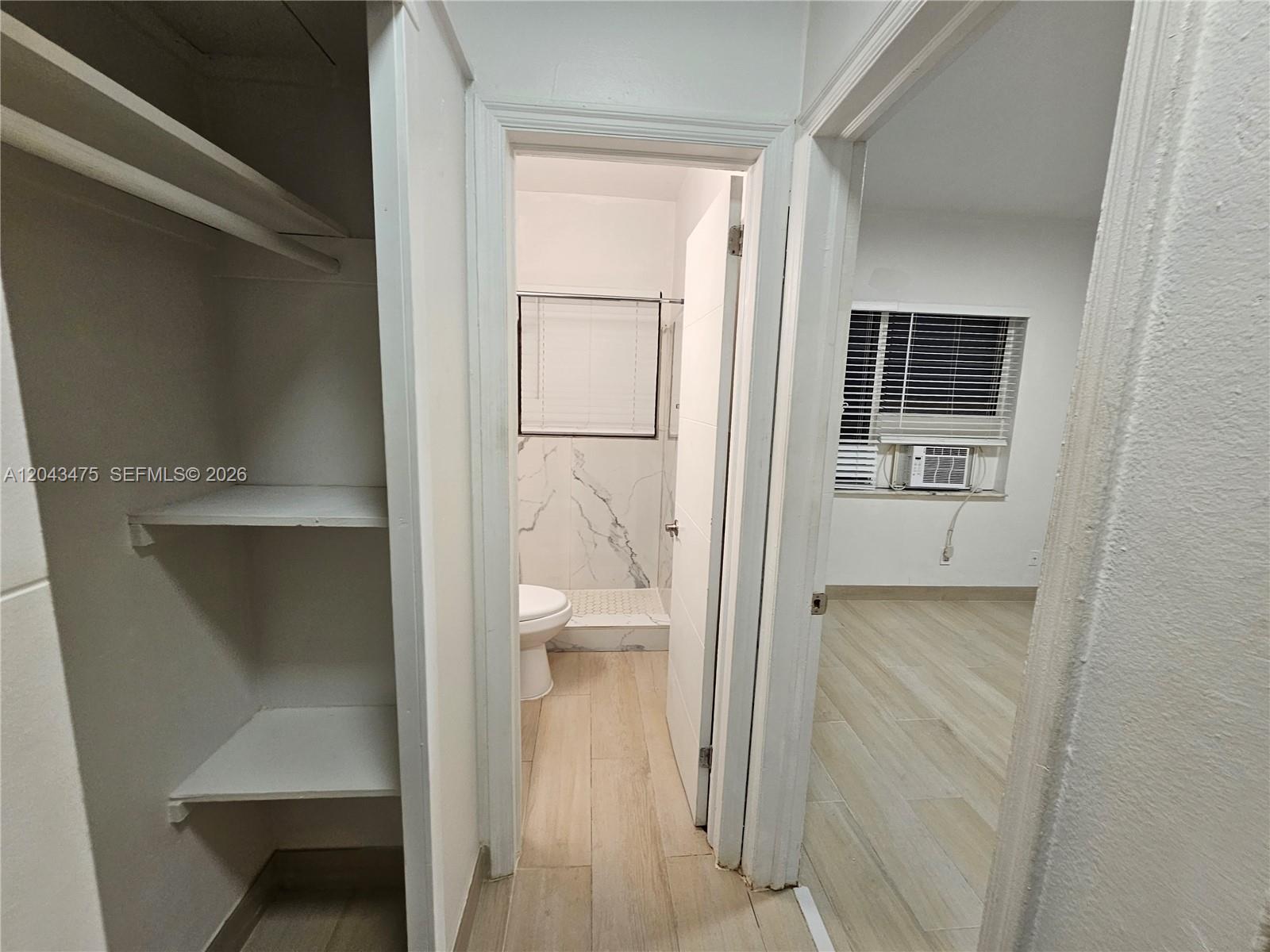 A view from a hallway into a bathroom with marble-style tile and an adjacent bedroom — 1723 Liberty St # 3, Hollywood FL 33020, HOLLYWOOD, FL
