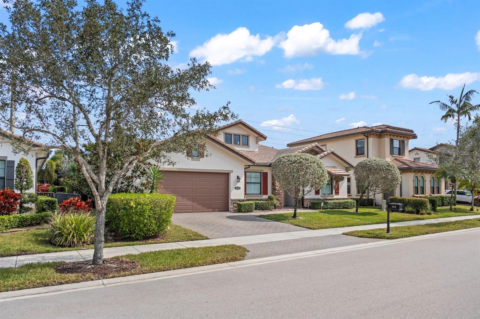 A single-story suburban house with a brown garage and a paved driveway under a blue sky — 8840 Watercrest Cir Circle E, Parkland FL 33076, PARKLAND, FL