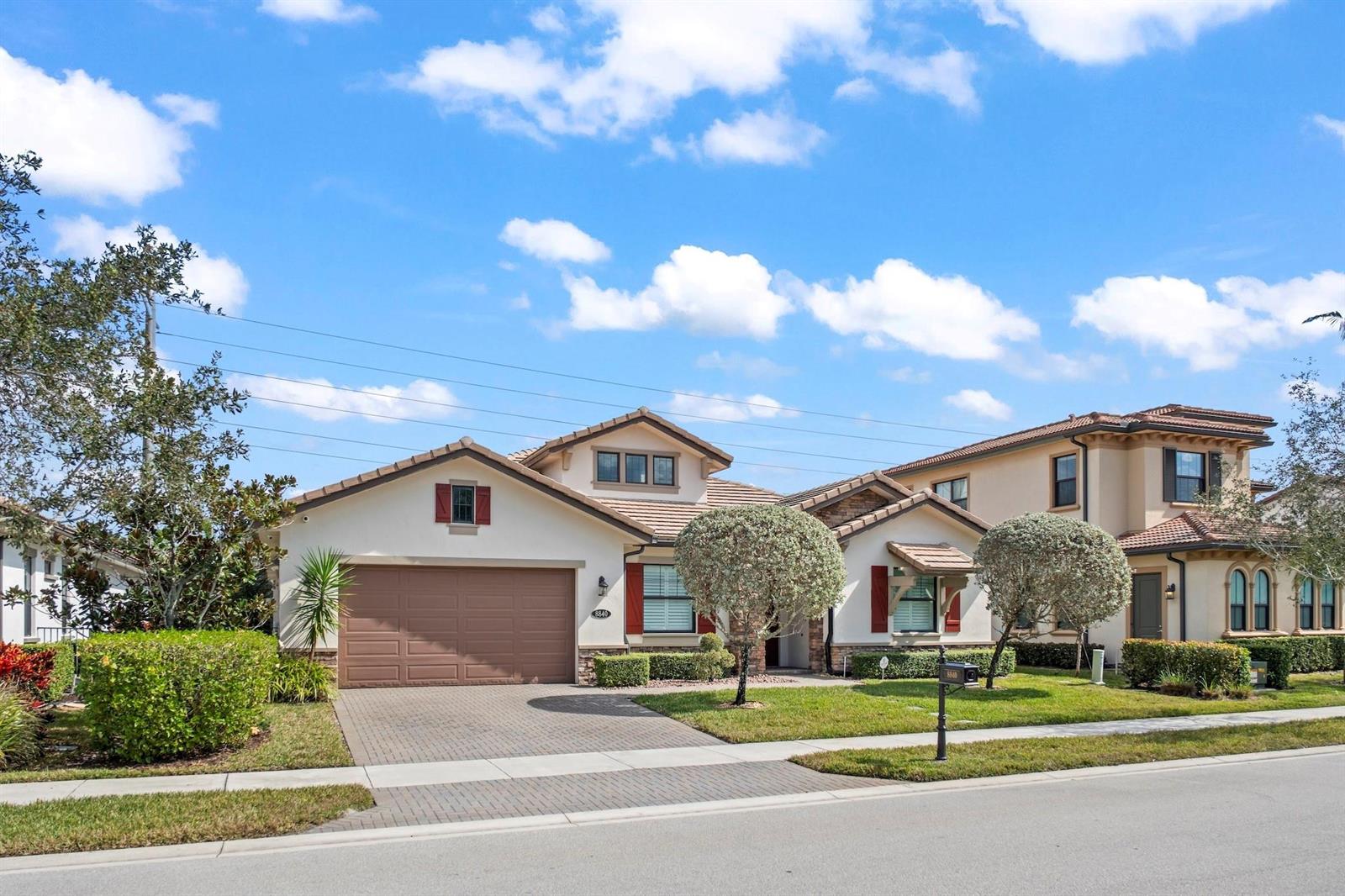 A single-story suburban house with a brown garage door, tiled roof, and landscaped front yard — 8840 Watercrest Cir Circle E, Parkland FL 33076, PARKLAND, FL