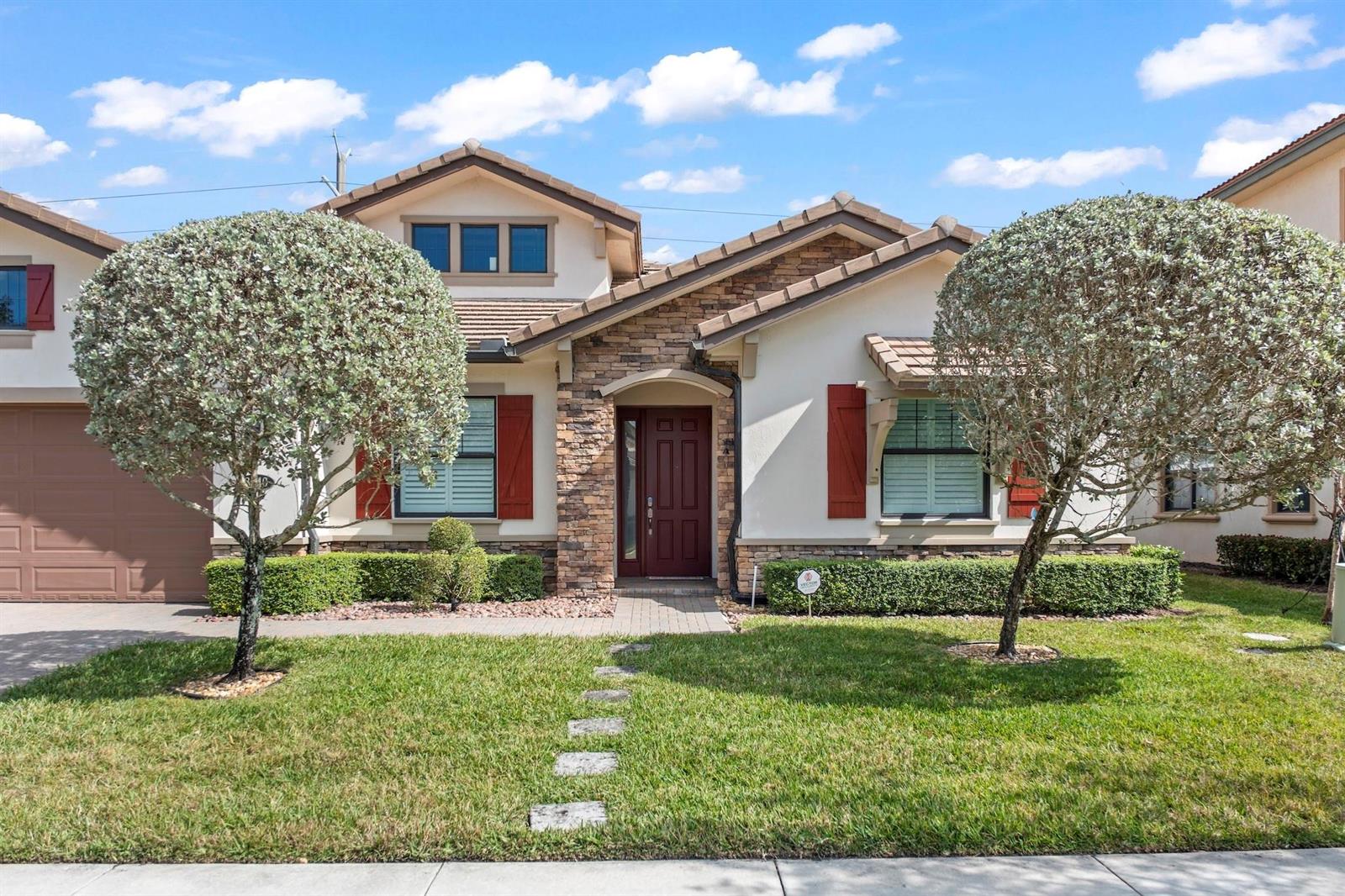 A single-story house with a stone facade, red shutters, and two manicured trees in front — 8840 Watercrest Cir Circle E, Parkland FL 33076, PARKLAND, FL
