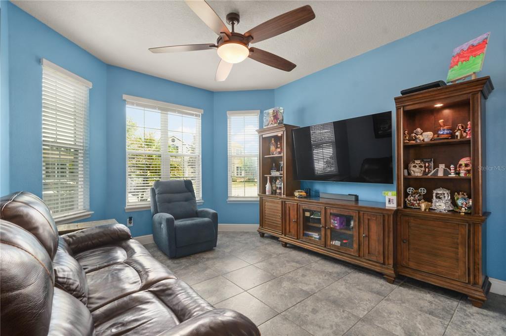 A living room features blue walls, tile flooring, a ceiling fan, and a large entertainment center — 5240 VILLA ROSA AVENUE, ST CLOUD, FL