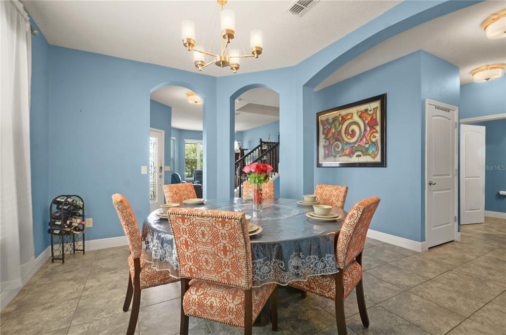 A dining room with blue walls, tile floors, a round table, and a chandelier — 5240 VILLA ROSA AVENUE, ST CLOUD, FL