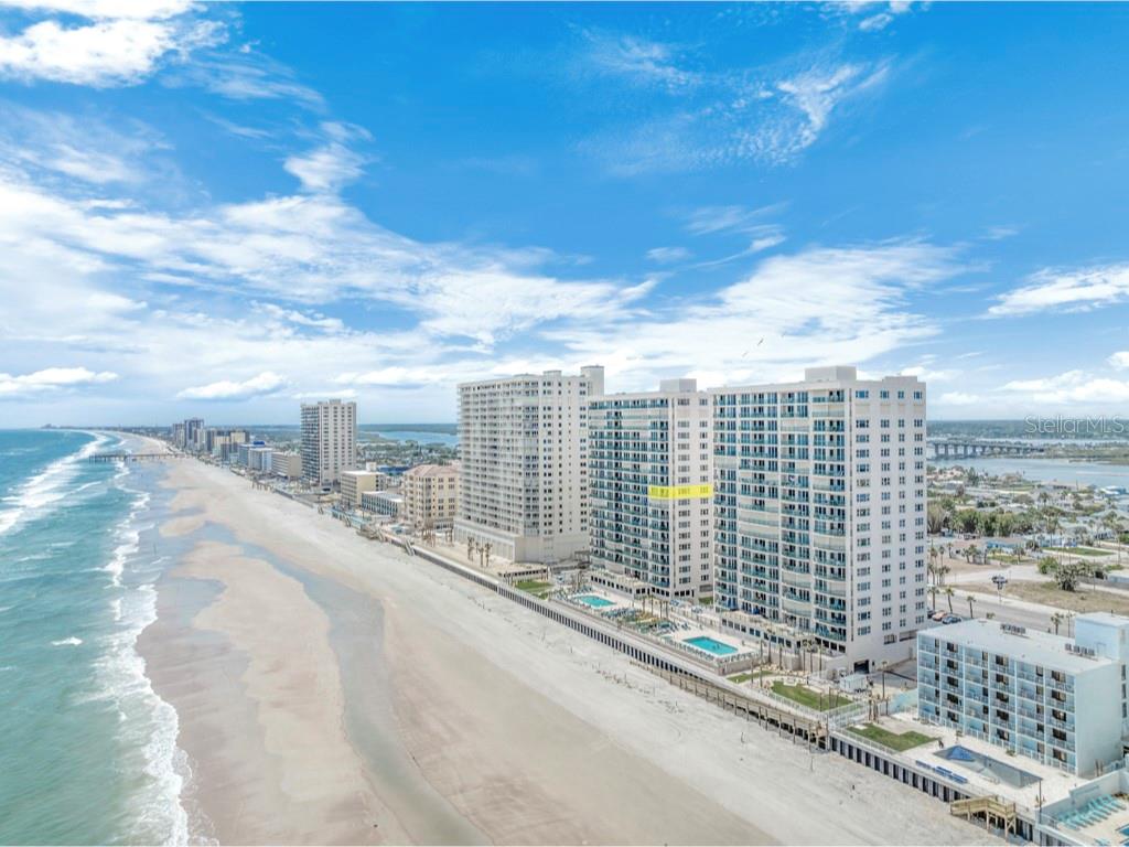 An aerial view of a beachfront high-rise condominium complex along a sandy coastline — 3315 S ATLANTIC AVENUE UNIT 1005, DAYTONA BEACH, FL