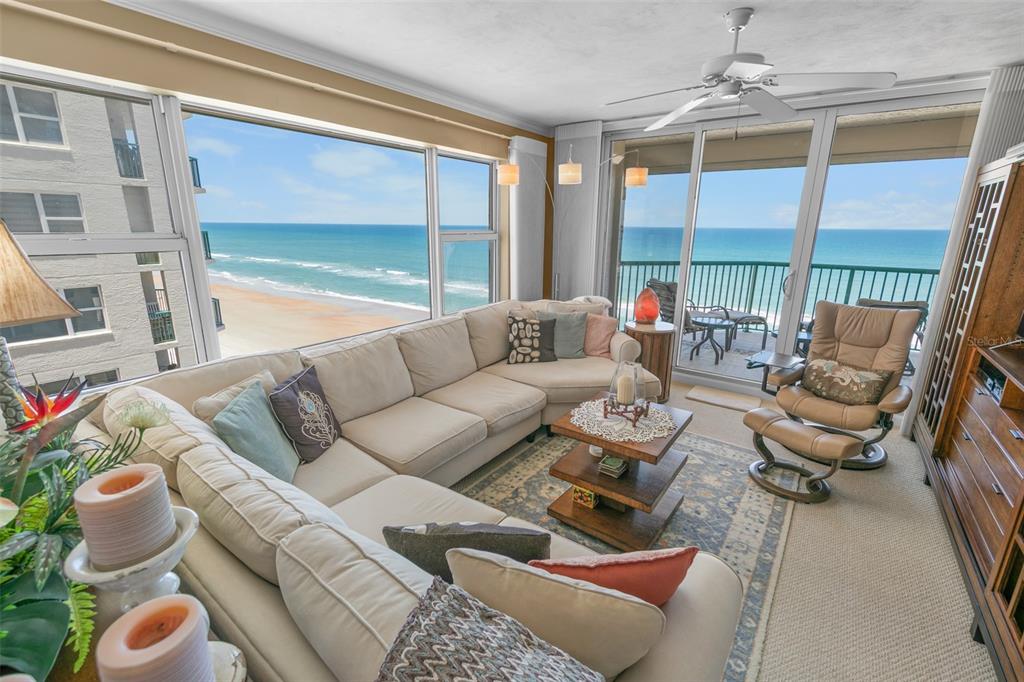 A living room with a large sectional sofa, a recliner, and floor-to-ceiling windows overlooking the ocean — 3315 S ATLANTIC AVENUE UNIT 1005, DAYTONA BEACH, FL