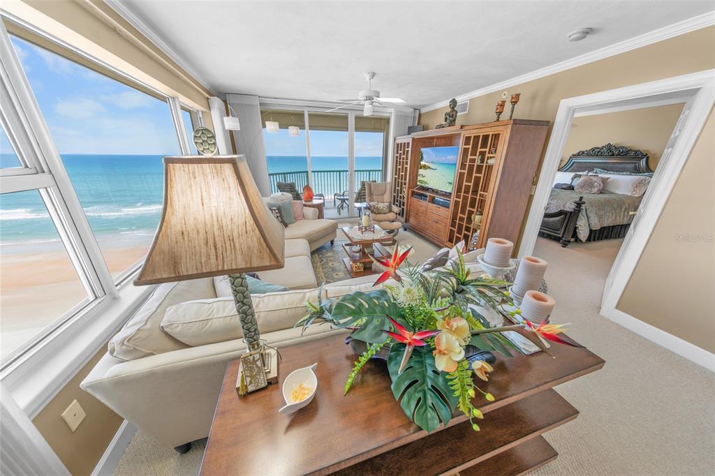 A living room with a view of the ocean, a sofa, and an adjacent bedroom — 3315 S ATLANTIC AVENUE UNIT 1005, DAYTONA BEACH, FL