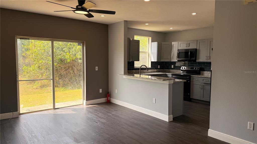 A kitchen features gray cabinets, granite countertops, a dark tile backsplash, and stainless steel appliances — 6236 OLIVEDALE DRIVE, RIVERVIEW, FL