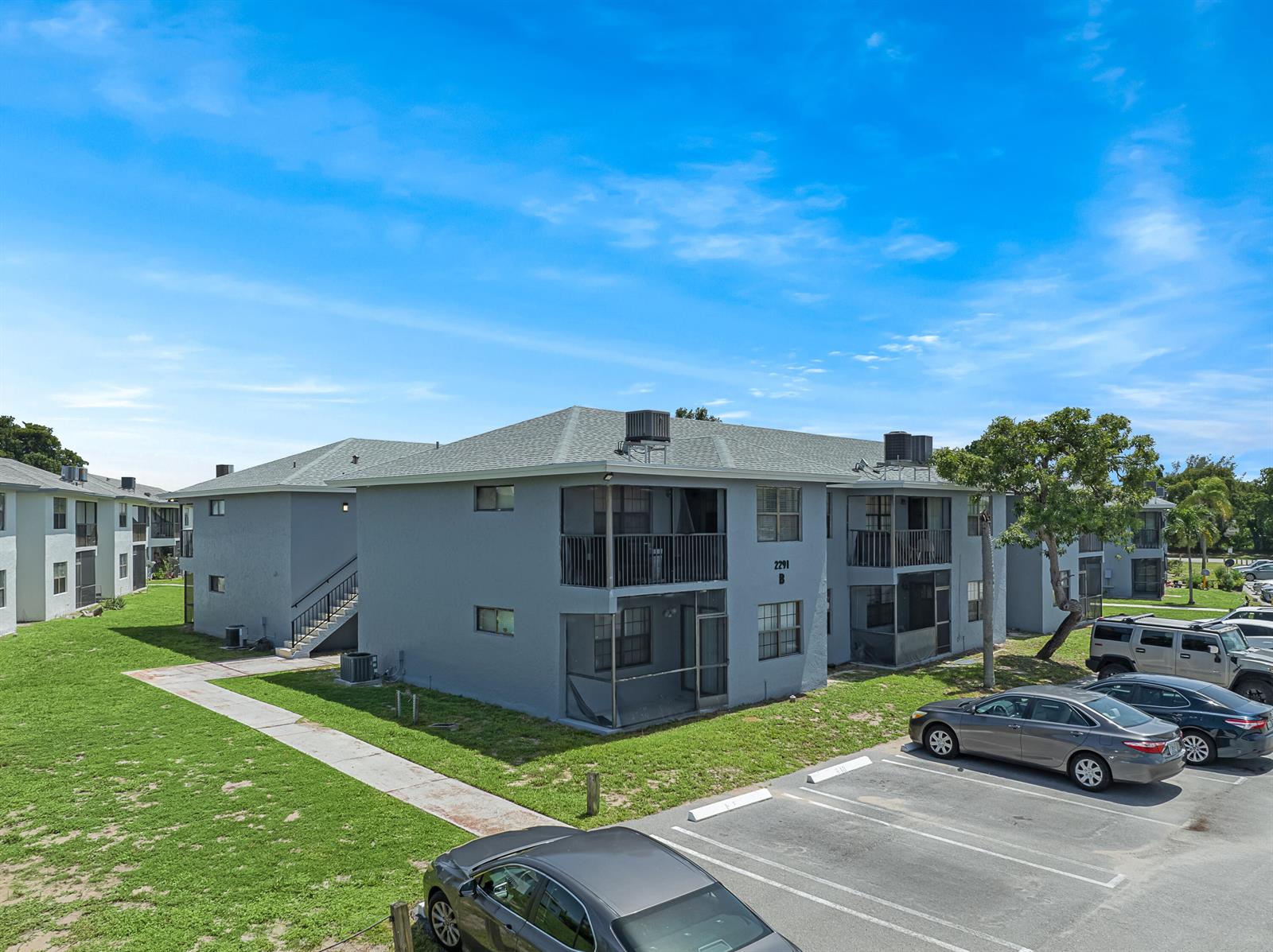 An exterior view of a two-story gray apartment building with screened balconies and parking spaces — 2291 Linton Ridge Circle # B4, Delray Beach FL 33444, DELRAY BEACH, FL