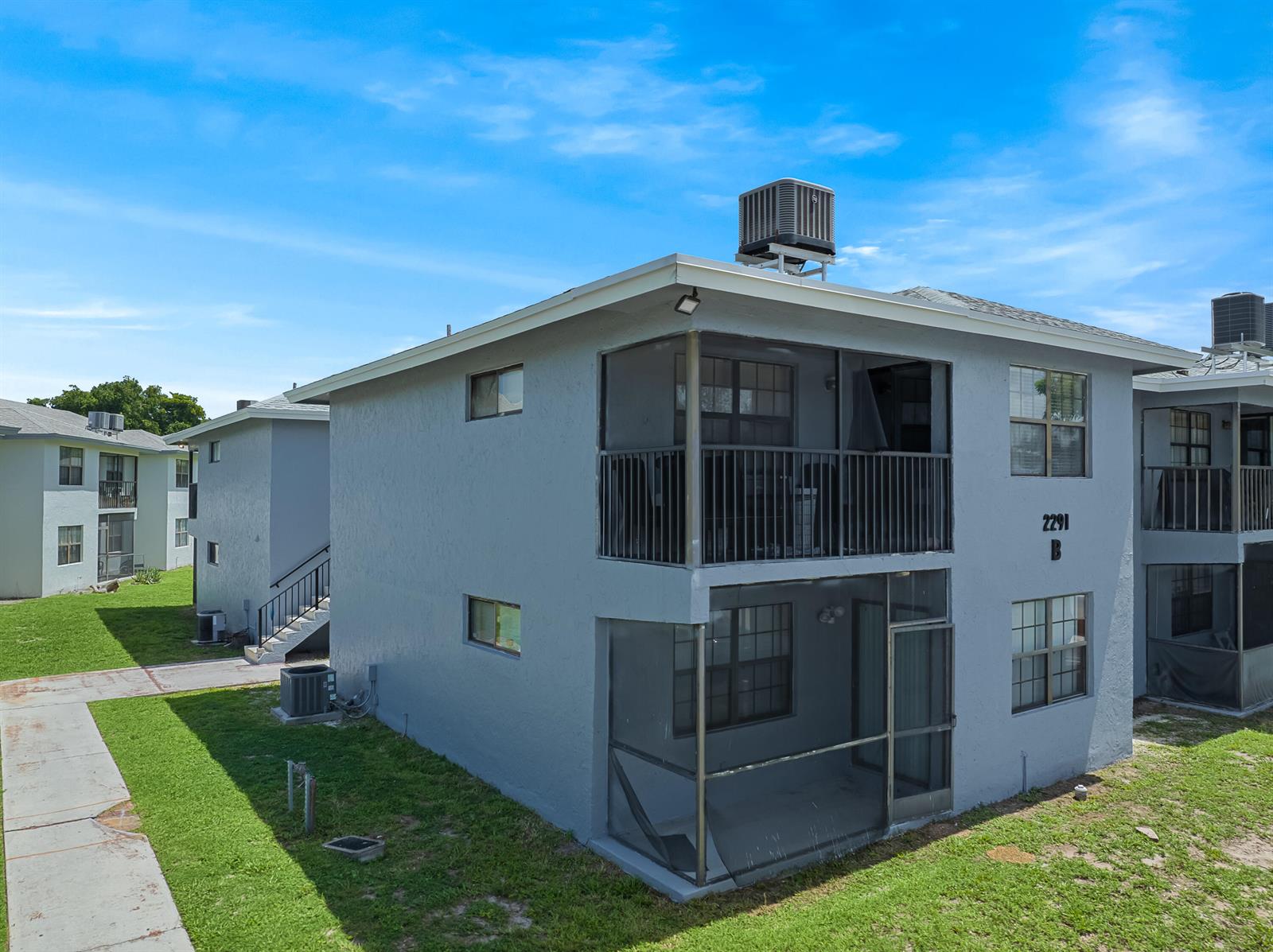 An exterior view of a two-story gray apartment building with screened-in balconies — 2291 Linton Ridge Circle # B4, Delray Beach FL 33444, DELRAY BEACH, FL