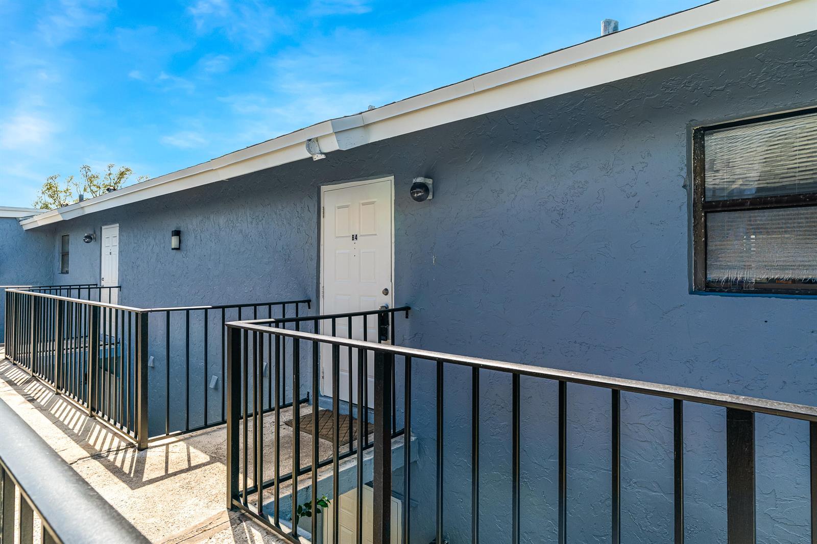 An exterior view of a blue apartment building with a walkway and black metal railings — 2291 Linton Ridge Circle # B4, Delray Beach FL 33444, DELRAY BEACH, FL
