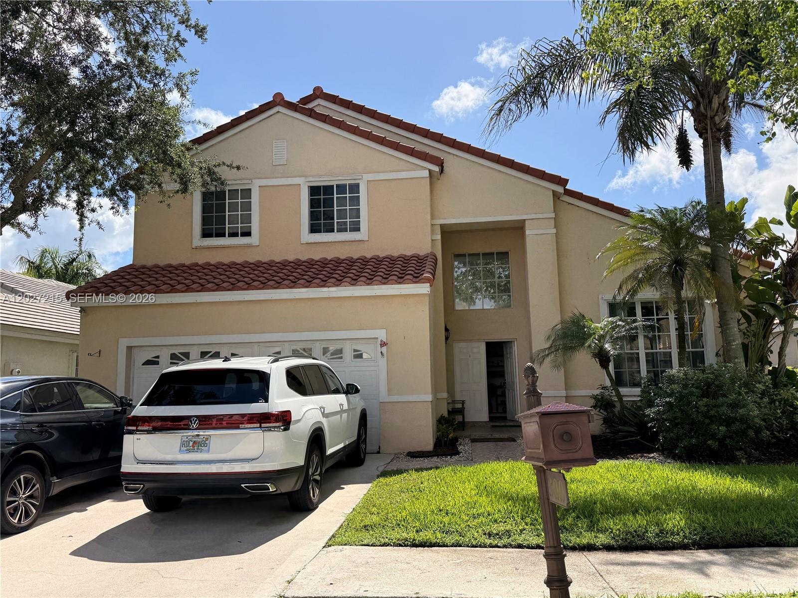 A two-story stucco house with a tile roof and a driveway featuring two parked cars — 300 Cameron Dr, Weston FL 33326, WESTON, FL