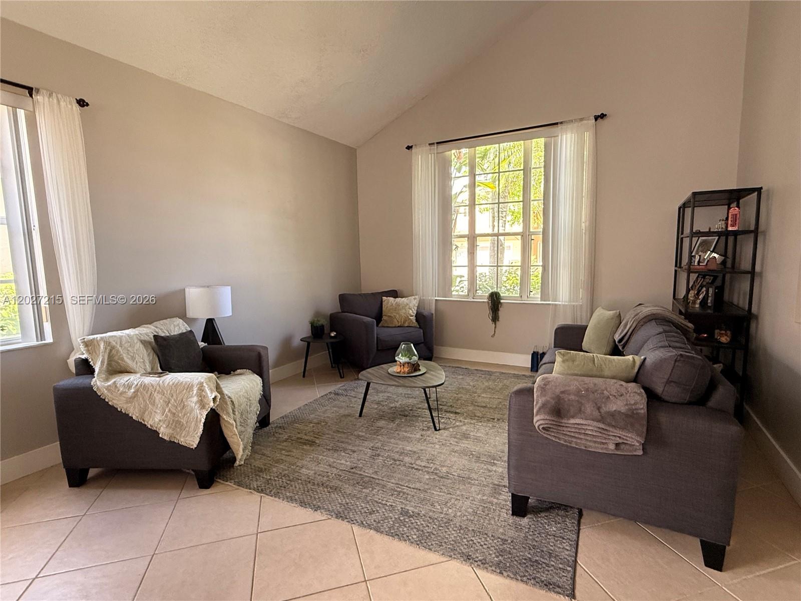 A living room features gray furniture, a patterned area rug, and large windows with curtains — 300 Cameron Dr, Weston FL 33326, WESTON, FL