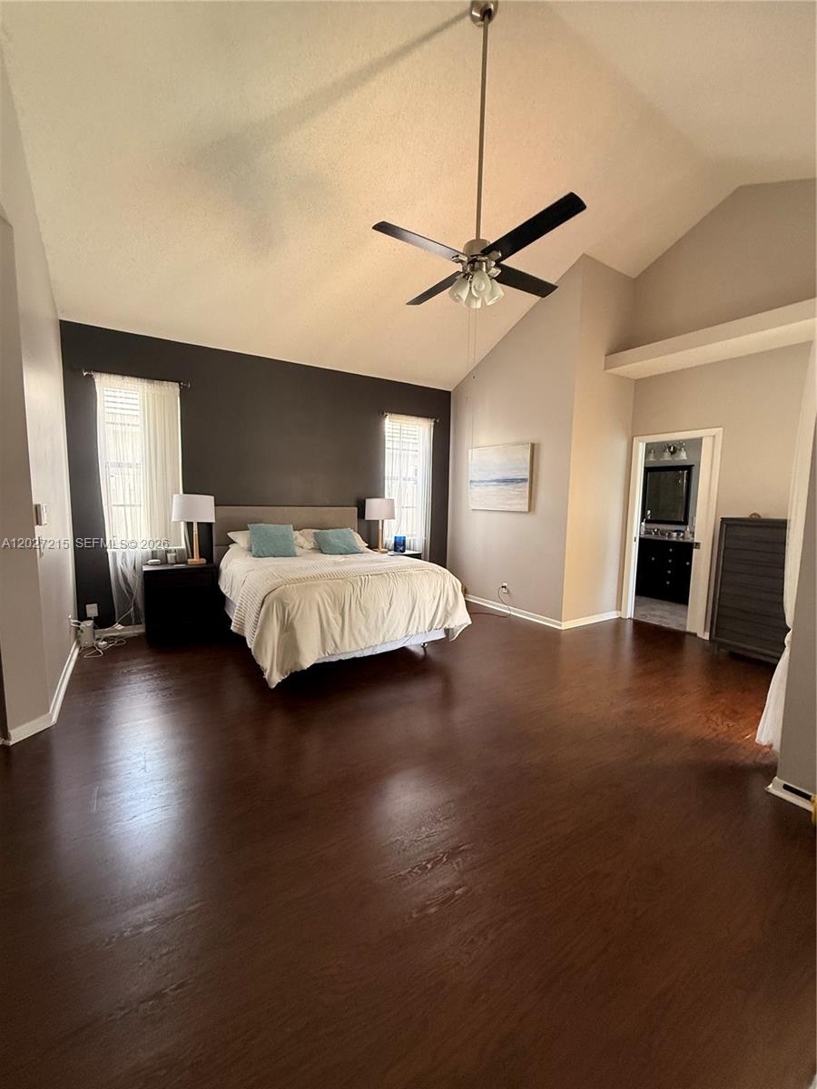 A bedroom features dark wood floors, a vaulted ceiling, and a dark accent wall — 300 Cameron Dr, Weston FL 33326, WESTON, FL
