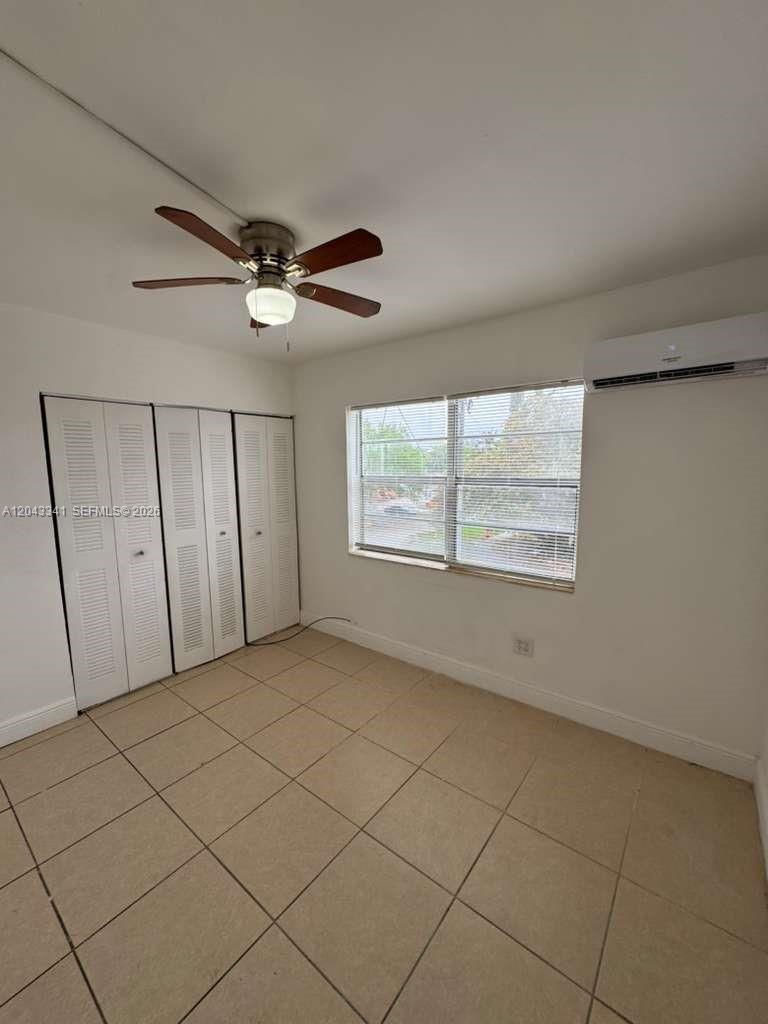A bedroom with tile flooring, a ceiling fan, a closet, and a wall-mounted air conditioner — NORTH MIAMI, FL