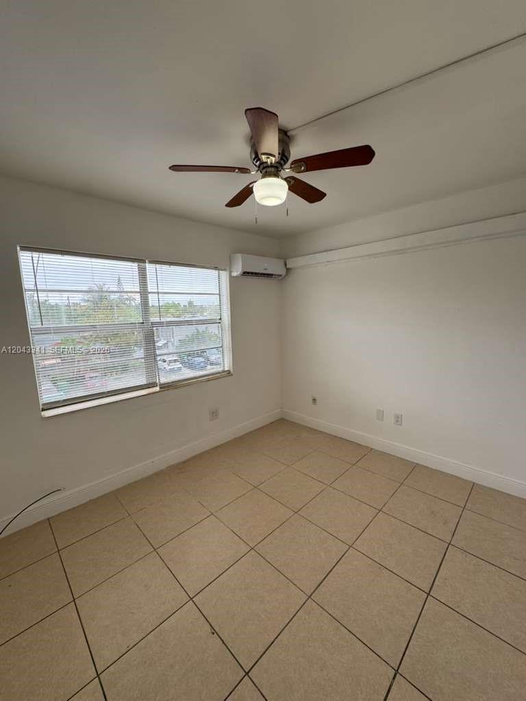 An empty room features beige tile flooring, a ceiling fan, and a window with blinds — NORTH MIAMI, FL