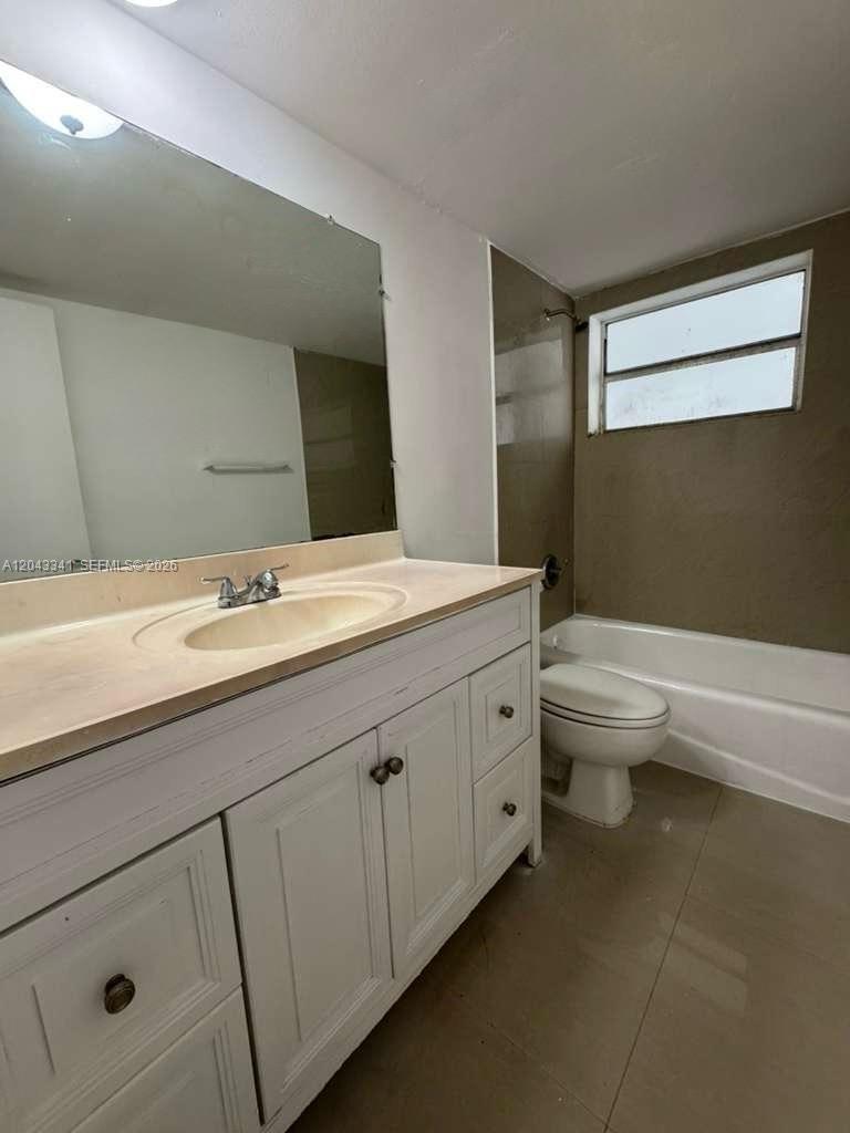 A bathroom features a white vanity with a beige countertop, a mirror, and a tub-shower — NORTH MIAMI, FL