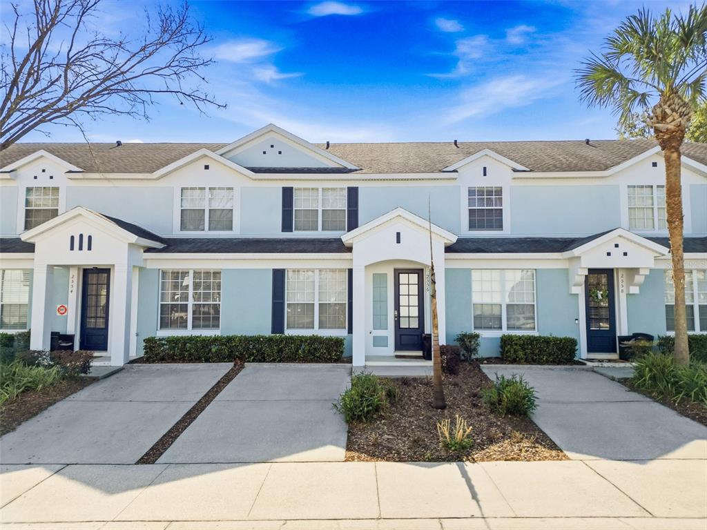 A row of three light blue townhouses with concrete driveways and small front landscaping — 2556 RENSHAW STREET, KISSIMMEE, FL