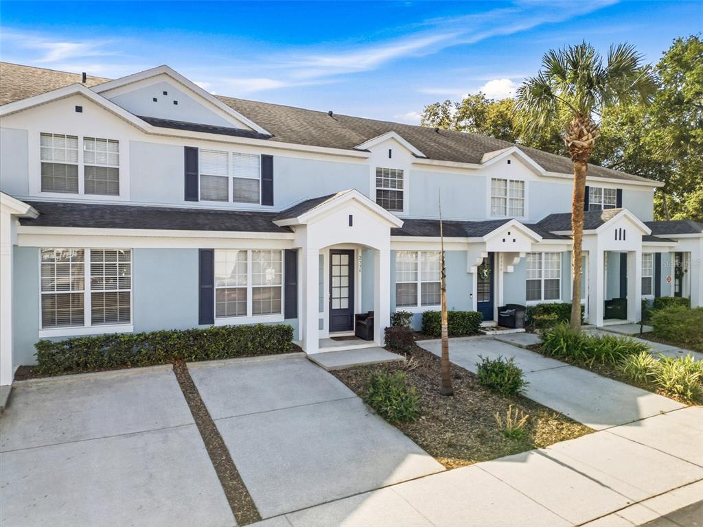A row of light blue two-story townhomes features concrete driveways and small front porches — 2556 RENSHAW STREET, KISSIMMEE, FL