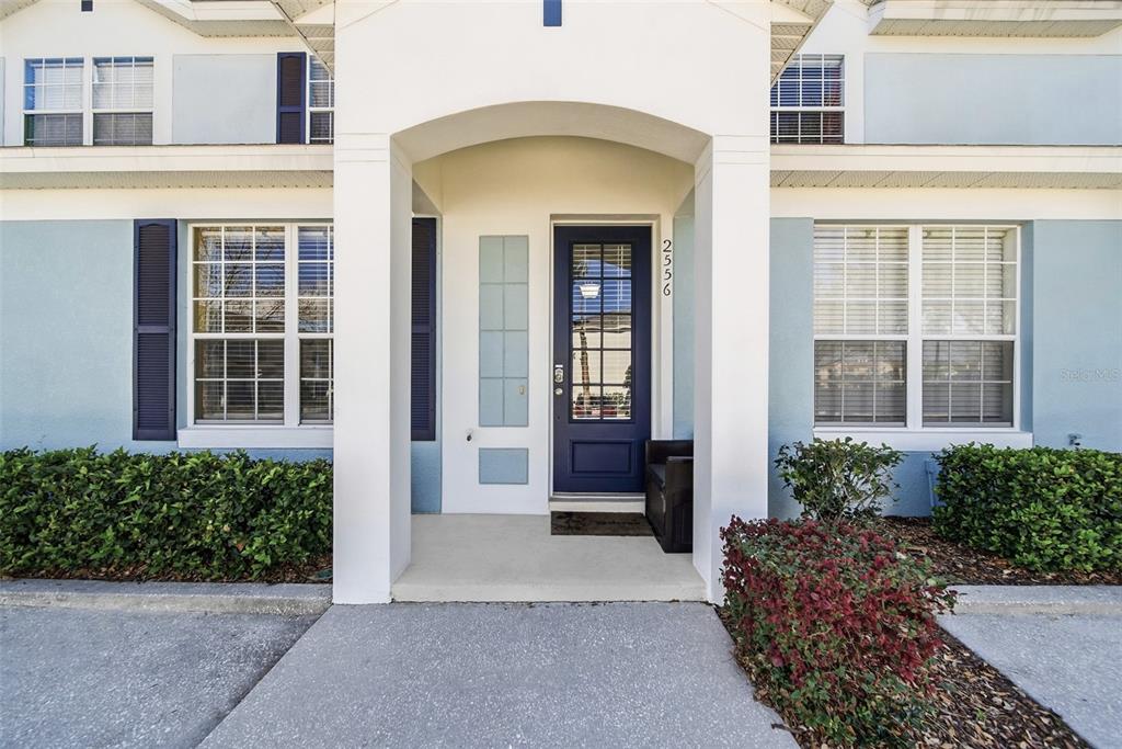 The exterior of a two-story home features a blue front door and white columns — 2556 RENSHAW STREET, KISSIMMEE, FL