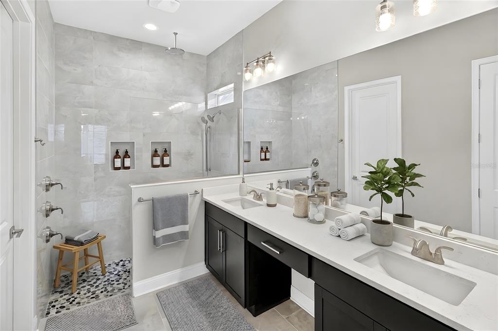 A modern bathroom features a walk-in shower with pebble flooring and a double vanity — 11943 SW 31ST ROAD, GAINESVILLE, FL