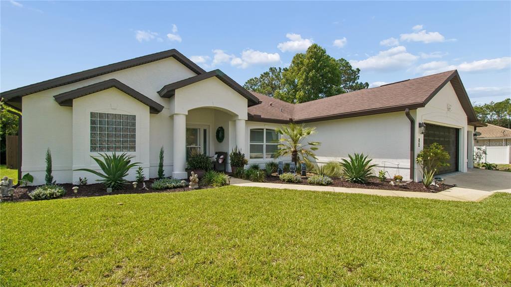 A single-story house with a white stucco exterior, a brown shingled roof, and a front lawn — 46 BROOKLYN LANE, PALM COAST, FL