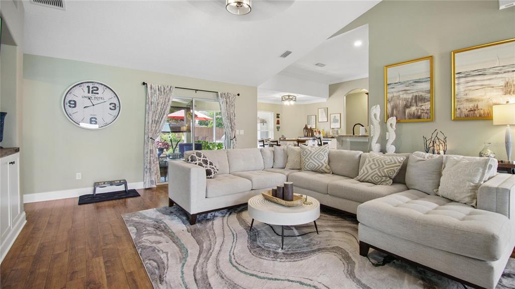 A living room features a large sectional sofa, a round coffee table, and hardwood floors — 46 BROOKLYN LANE, PALM COAST, FL