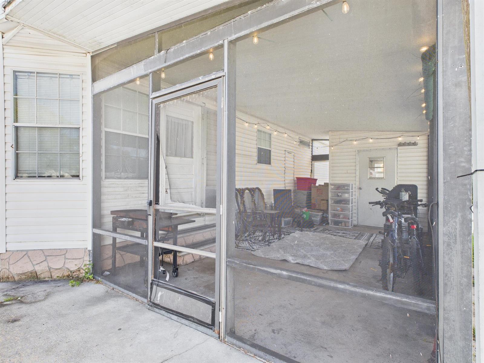 A screened-in porch with a concrete floor, a screen door, and various stored items — 102 NE 8th Avenue, Okeechobee FL 34972, OKEECHOBEE, FL