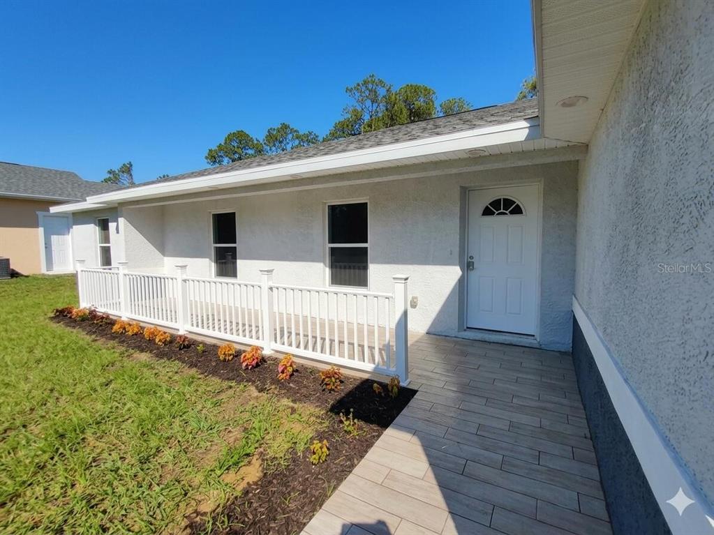 A white house exterior features a tiled porch, a white front door, and a white railing — 5609 LAKEWOOD ROAD, SEBRING, FL
